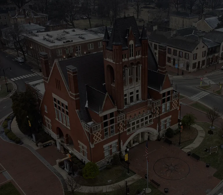 Aerial view of a historic red brick building with Gothic architectural features in a town square.