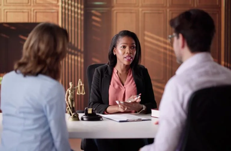 Professional woman lawyer consulting with a man and woman in a formal office setting.