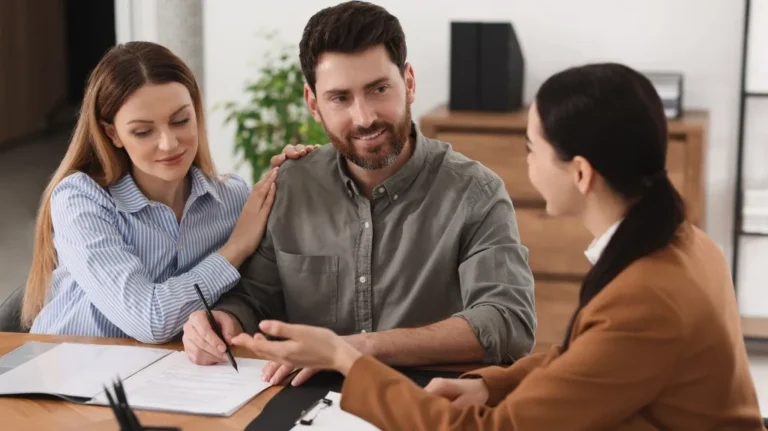 Three people engaged in a professional meeting, reviewing Family Law documents at a desk.